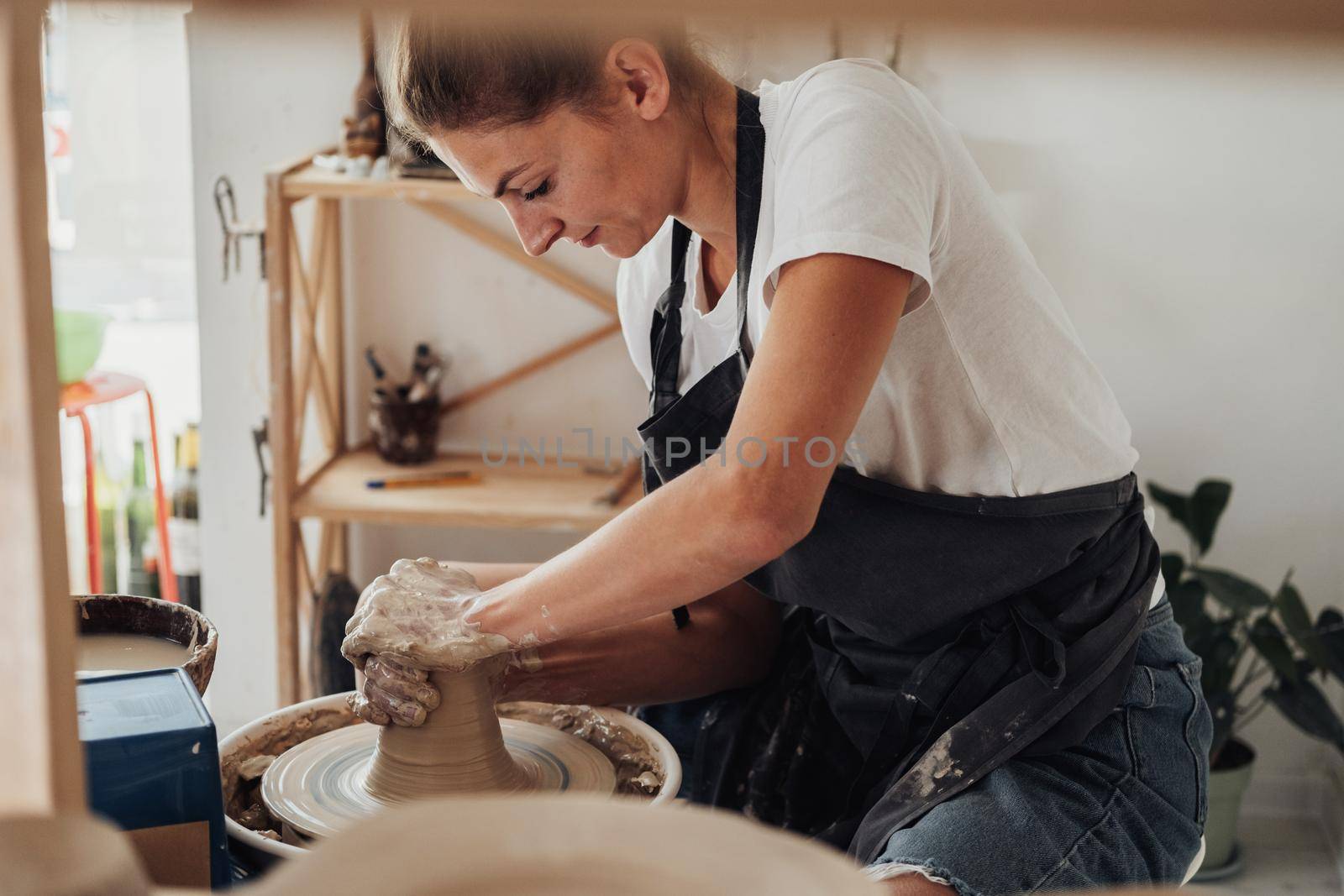 Potter Master at Work, Young Caucasian Woman Creating Clay Pot on a Pottery Wheel in Her Studio by Romvy