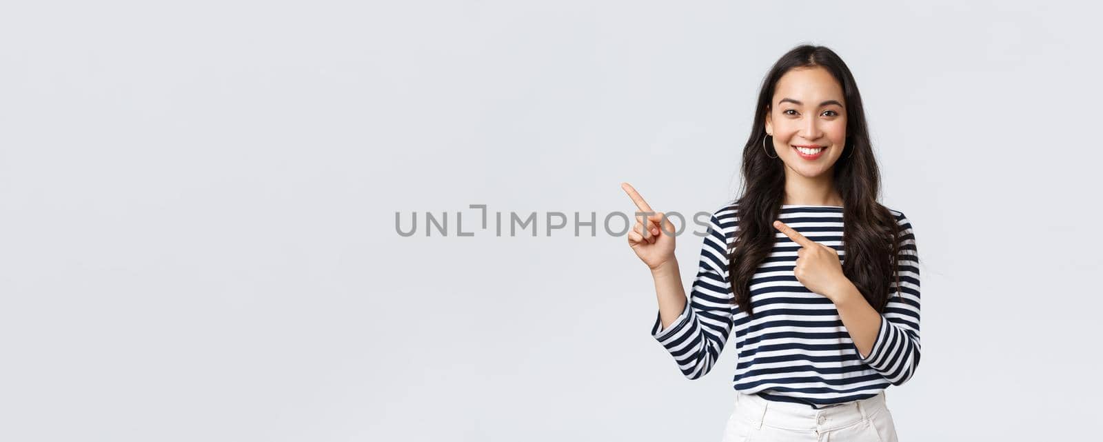 Lifestyle, people emotions and casual concept. Good-looking young korean female advertise product, smiling camera excited and pointing fingers upper left corner at promo banner by Benzoix