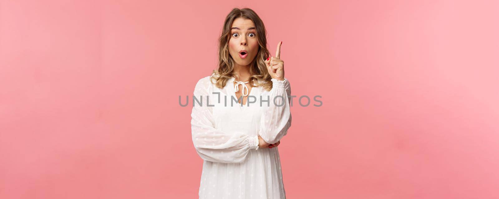 Beauty, fashion and women concept. Portrait of amazed and excited feminine blond girl in white dress, open mouth gasping amused and raise one finger, have suggestion, found solution by Benzoix