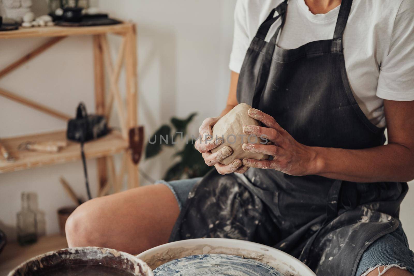 Unrecognisable Female Potter Master Preparing Pile of Clay to Creating Pot on a Pottery Wheel in Her Ceramic Studio by Romvy
