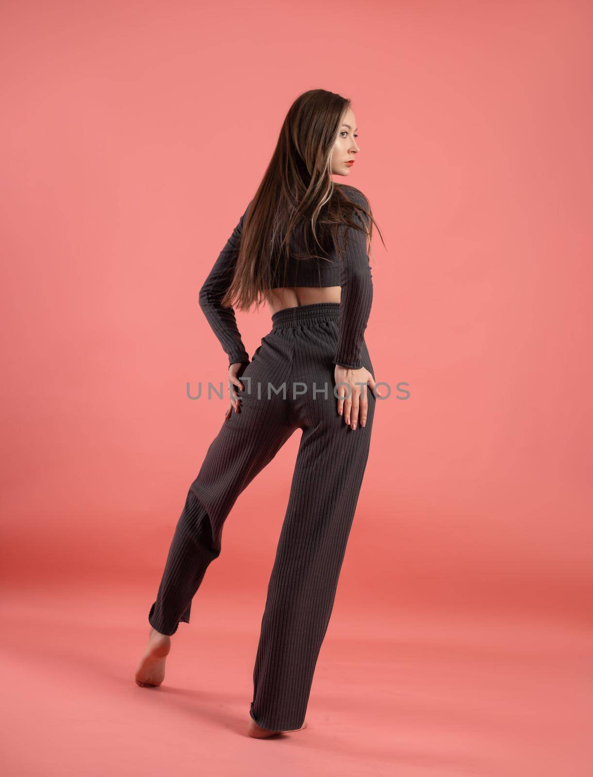 a beautiful slender girl in a stylish home suit on a pink background