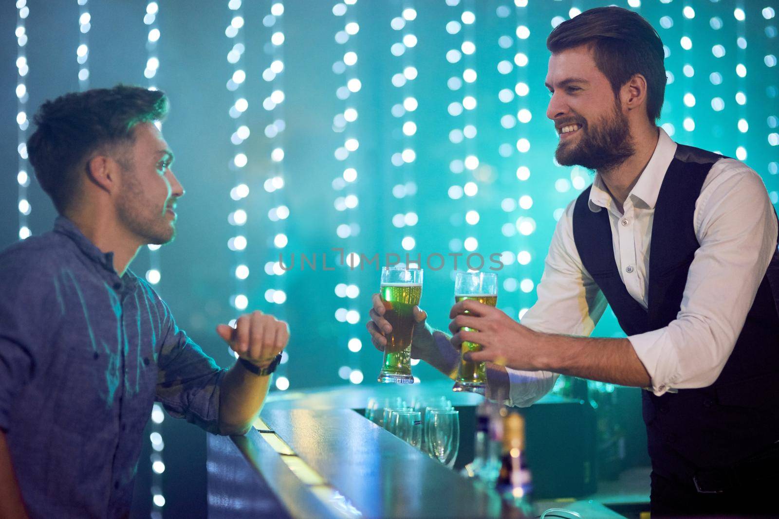 Two beers ready to go. Cropped shot of a bartender serving drinks to a man in a nightclub. by YuriArcurs
