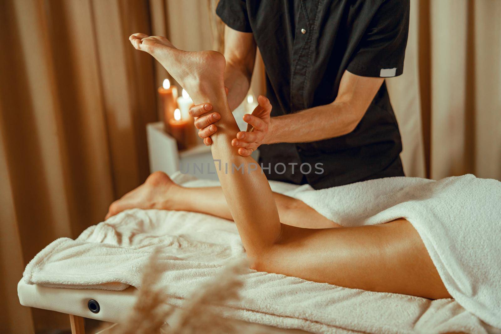 Professional male masseur doing foot massage female client in spa salon. Therapy, resort
