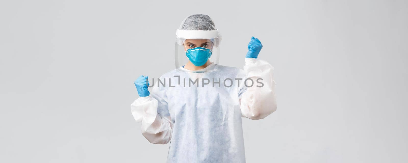 Covid-19, preventing virus, healthcare workers and quarantine concept. Confident doctor in personal protective equipment, face mask, cheering, invent coronavirus vaccine, determined cure patient.