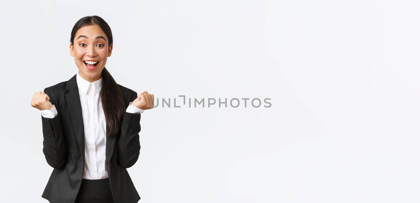 Relieved happy female office manager, successful businesswoman achieve goal, winning and feeling rejoice, fist pump and shouting yes satisfied, standing white background upbeat.