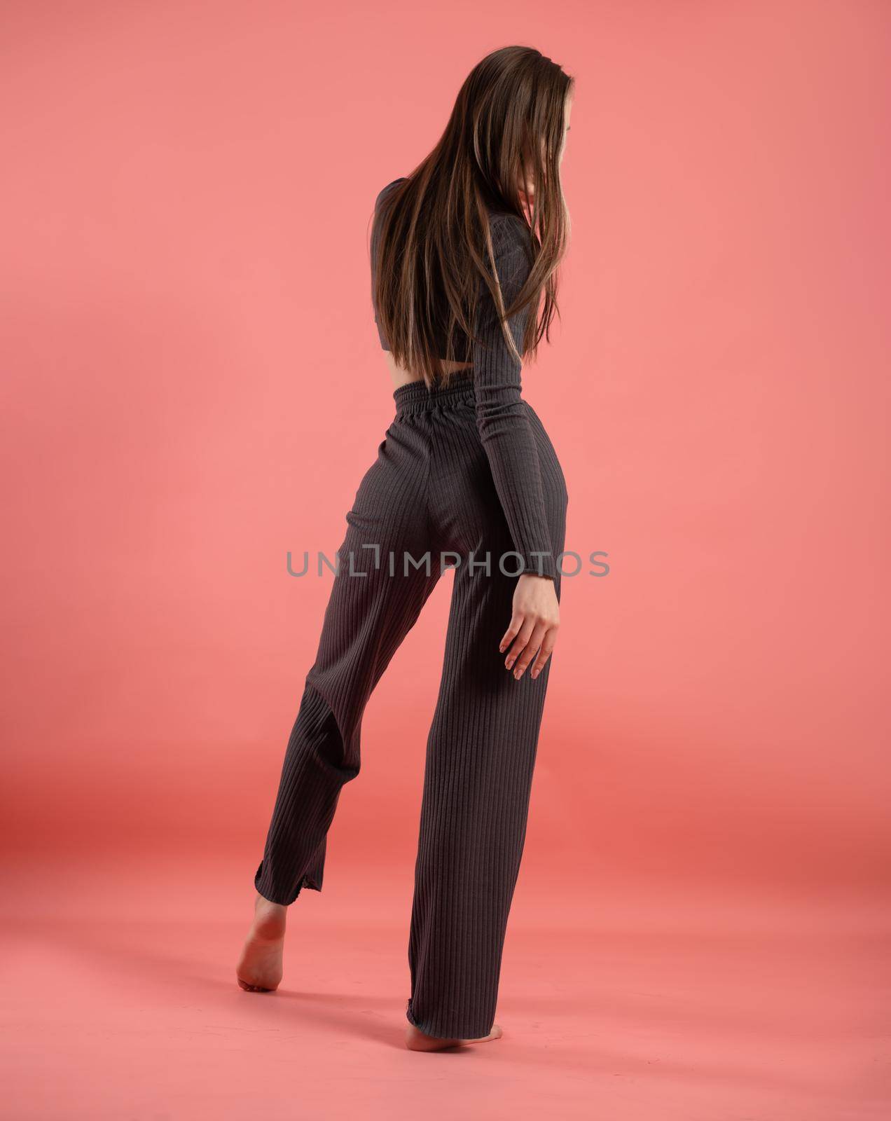 a beautiful slender girl in a stylish home suit on a pink background