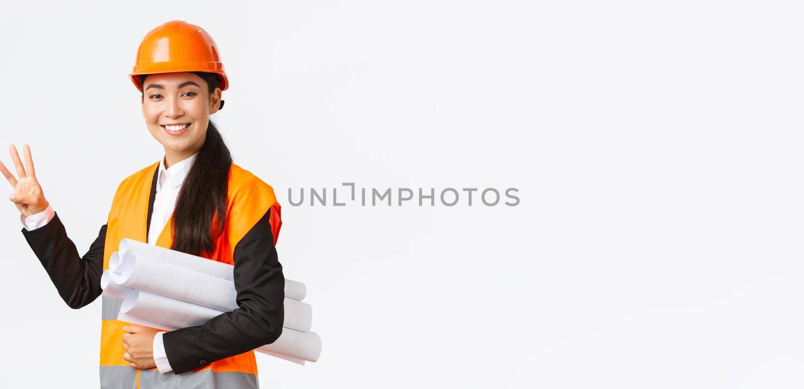 Smiling asian female architect at construction area, building estates, showing number three, carry blueprint as wearing safety helmet, giving fixed time for task done, white background.