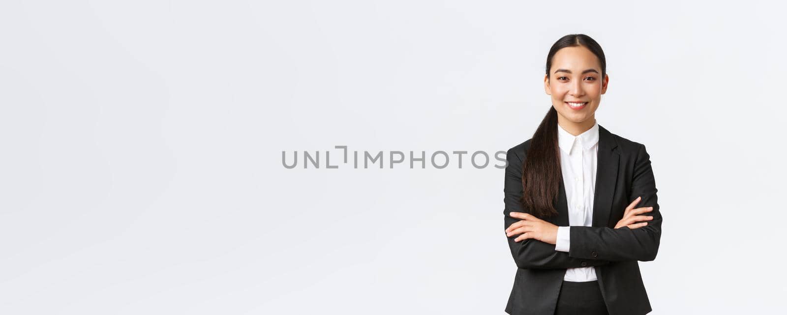 Successful young asian businesswoman in suit ready do business, cross arms confident and smiling. Female entrepreneur determined to win. Happy saleswoman talking to clients, white background.