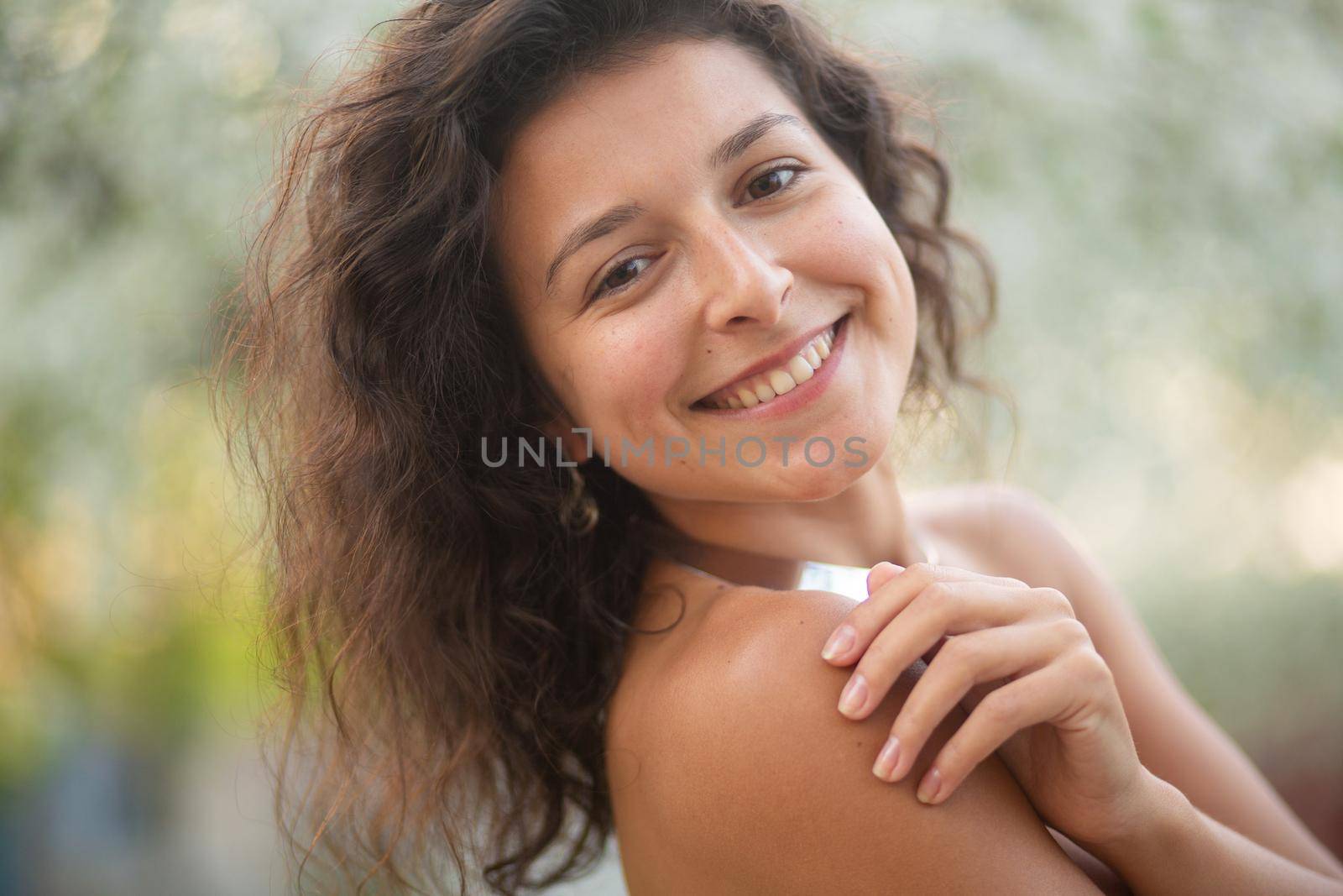 Portrait of a young laughing sexy brunette girl with a necklace around her neck.