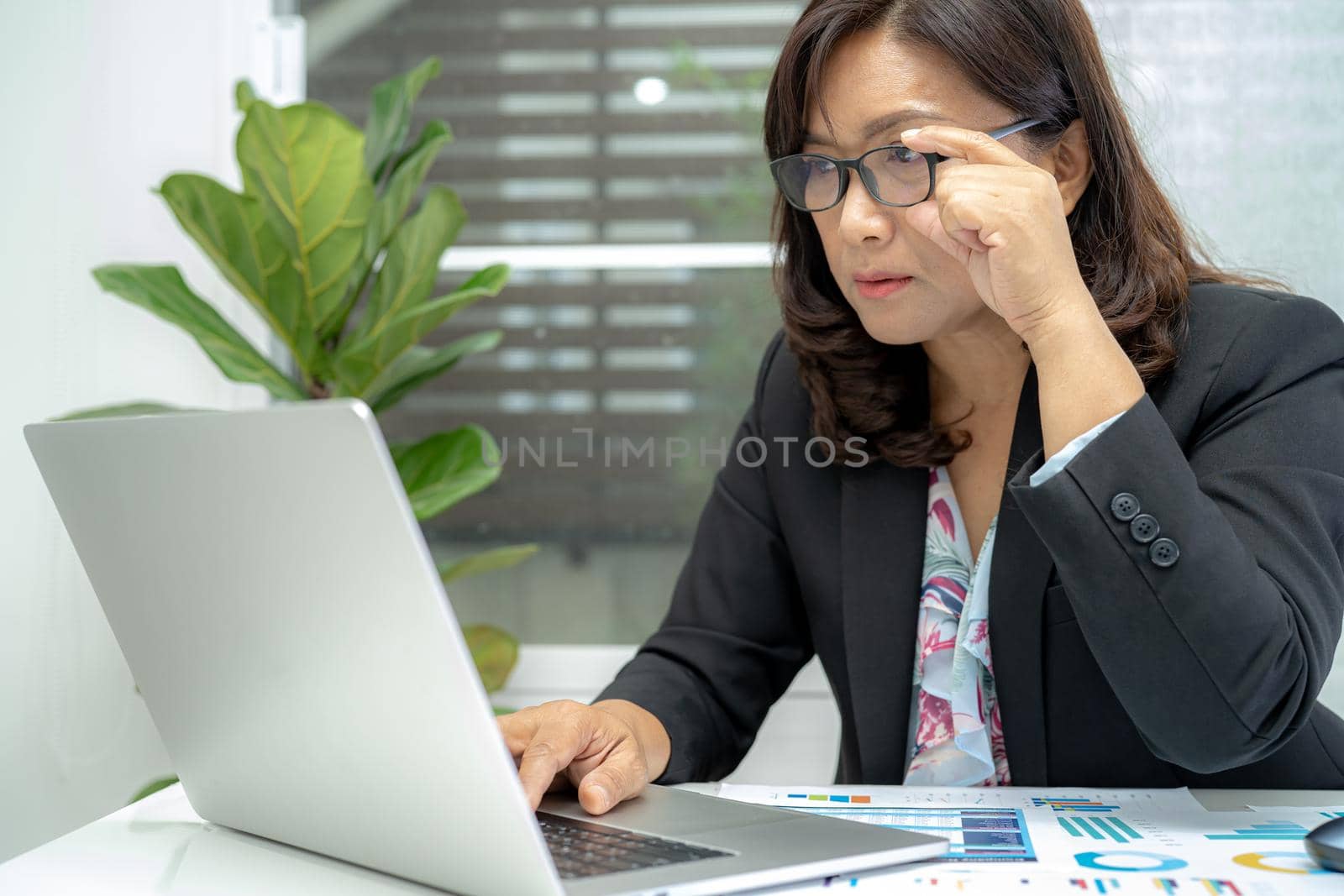 Asian accountant type keyboard to enter information, working, calculate and analyzing report project accounting with notebook in modern office, finance and business concept.