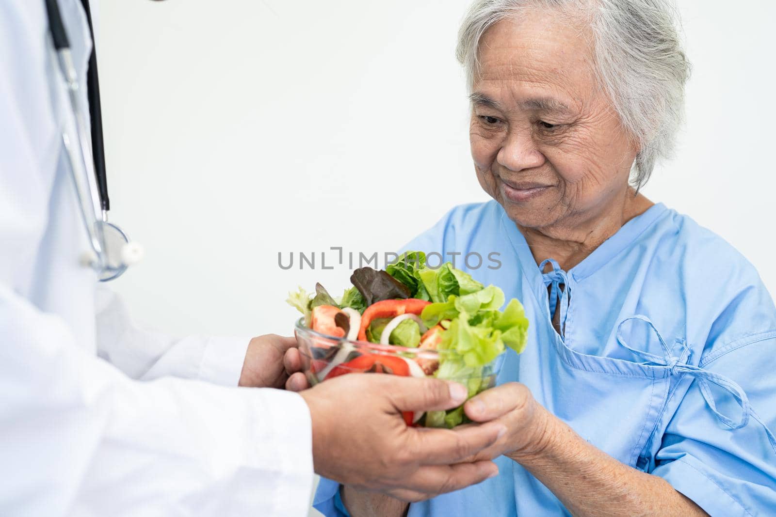 Asian senior or elderly old lady woman patient eating breakfast vegetable healthy food with hope and happy while sitting and hungry on bed in hospital.