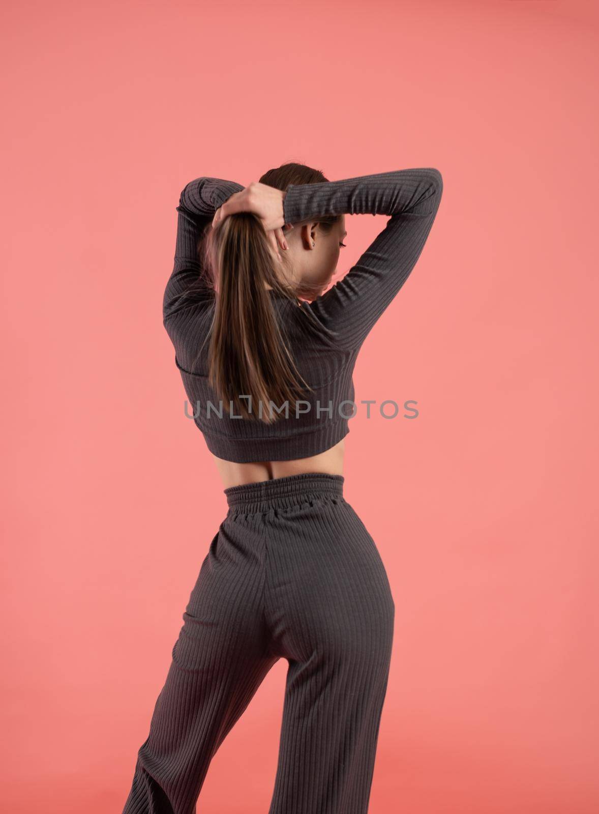 a beautiful slender girl in a stylish home suit on a pink background