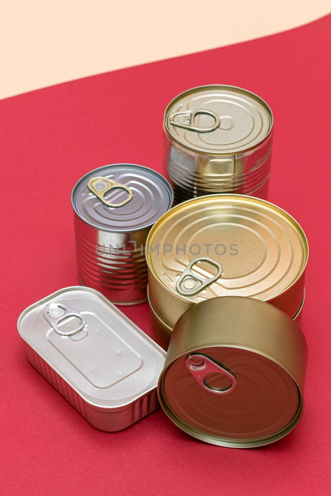 A Group of Stacked Tin Cans with Blank Edges on Red Background. Canned Food. Different Aluminum Cans for Safe and Long Term Storage of Food. Steel Sealed Food Storage Containers