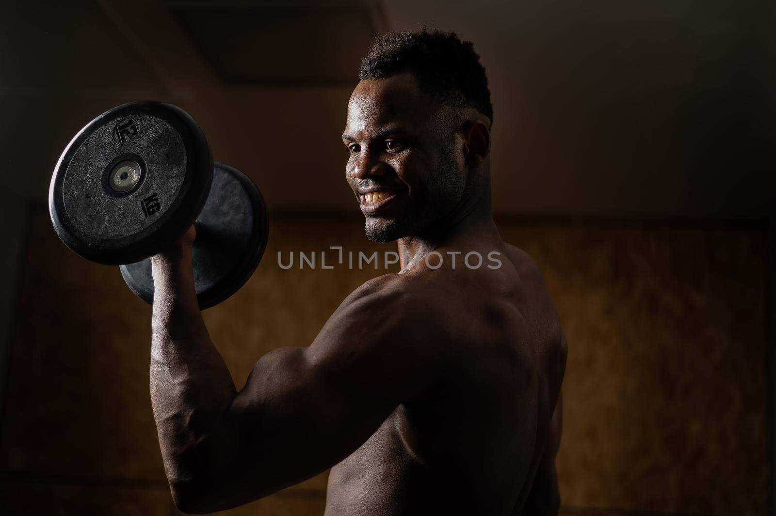 Attractive african american man smiling and doing exercise with dumbbells. by mrwed54