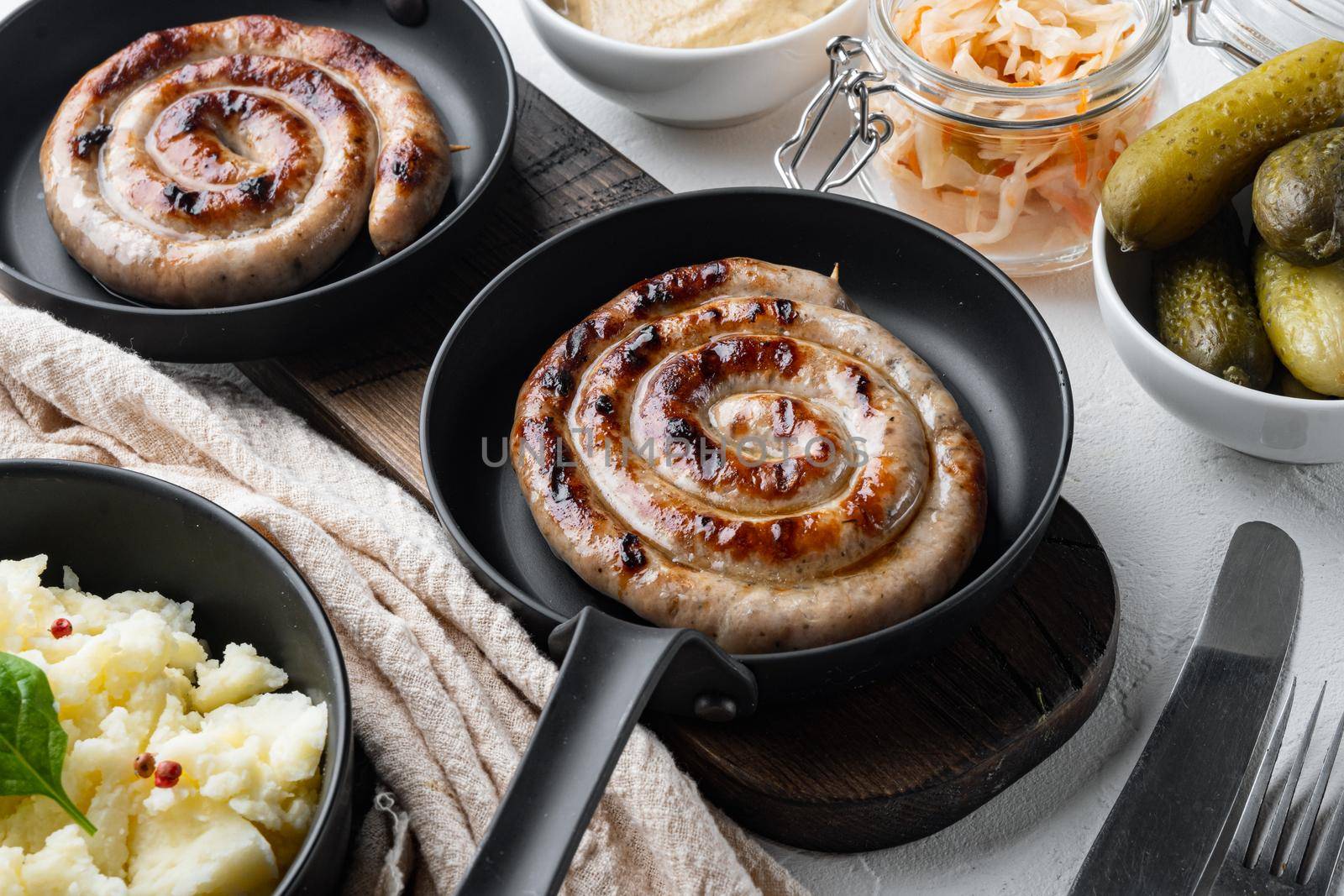 Grilled Spiral sausage set in cast iron frying pan, on white background