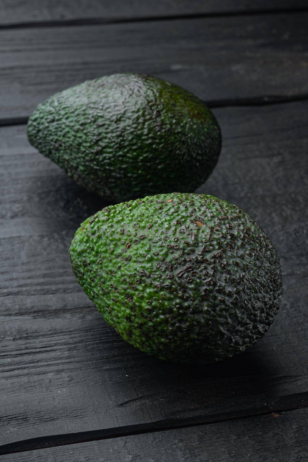 Ripe pair of green avocado, on black wooden background by Ilianesolenyi