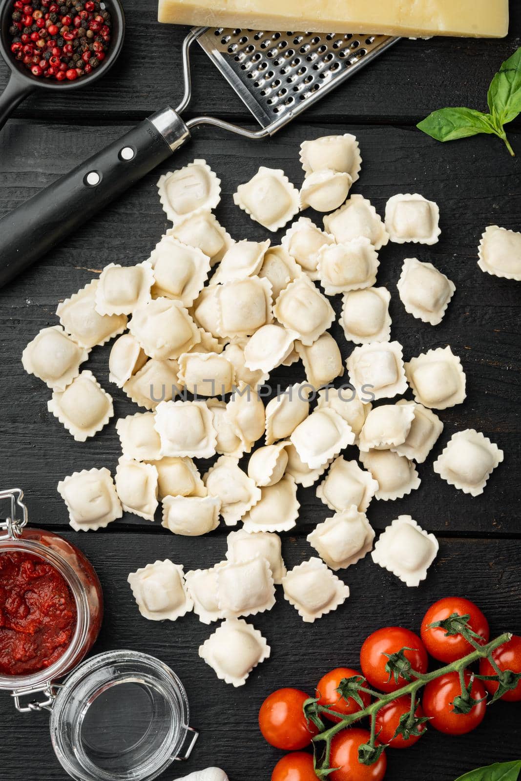 Italian Ravioli ingredients with fresh ricotta leaves and tomatoes set, on black wooden table background, top view flat lay