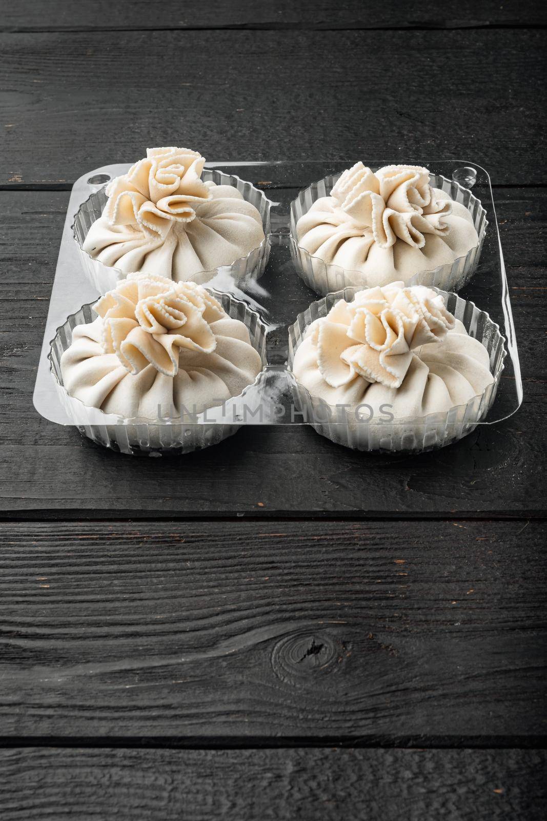 Homemade, traditional chinese pan fried dumplings, in plastic tray, on black wooden table background, with copy space for text by Ilianesolenyi