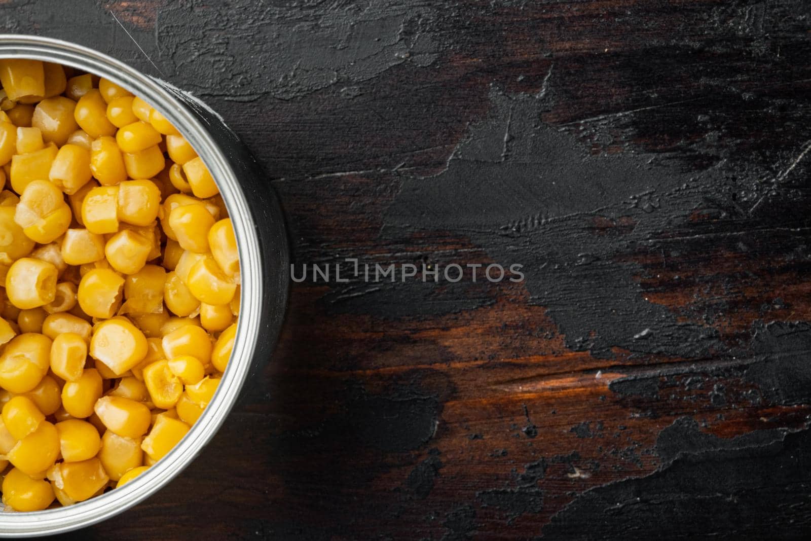 Canned sweet corn in can, on old dark wooden table background, top view flat lay with copy space for text