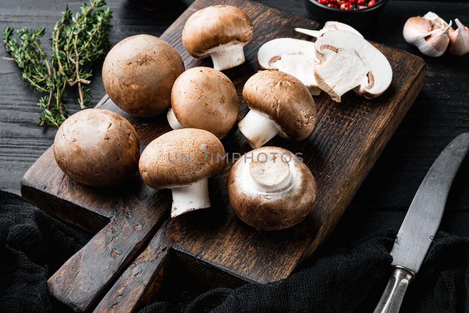 Brown champignons mushroom, on black wooden table background by Ilianesolenyi