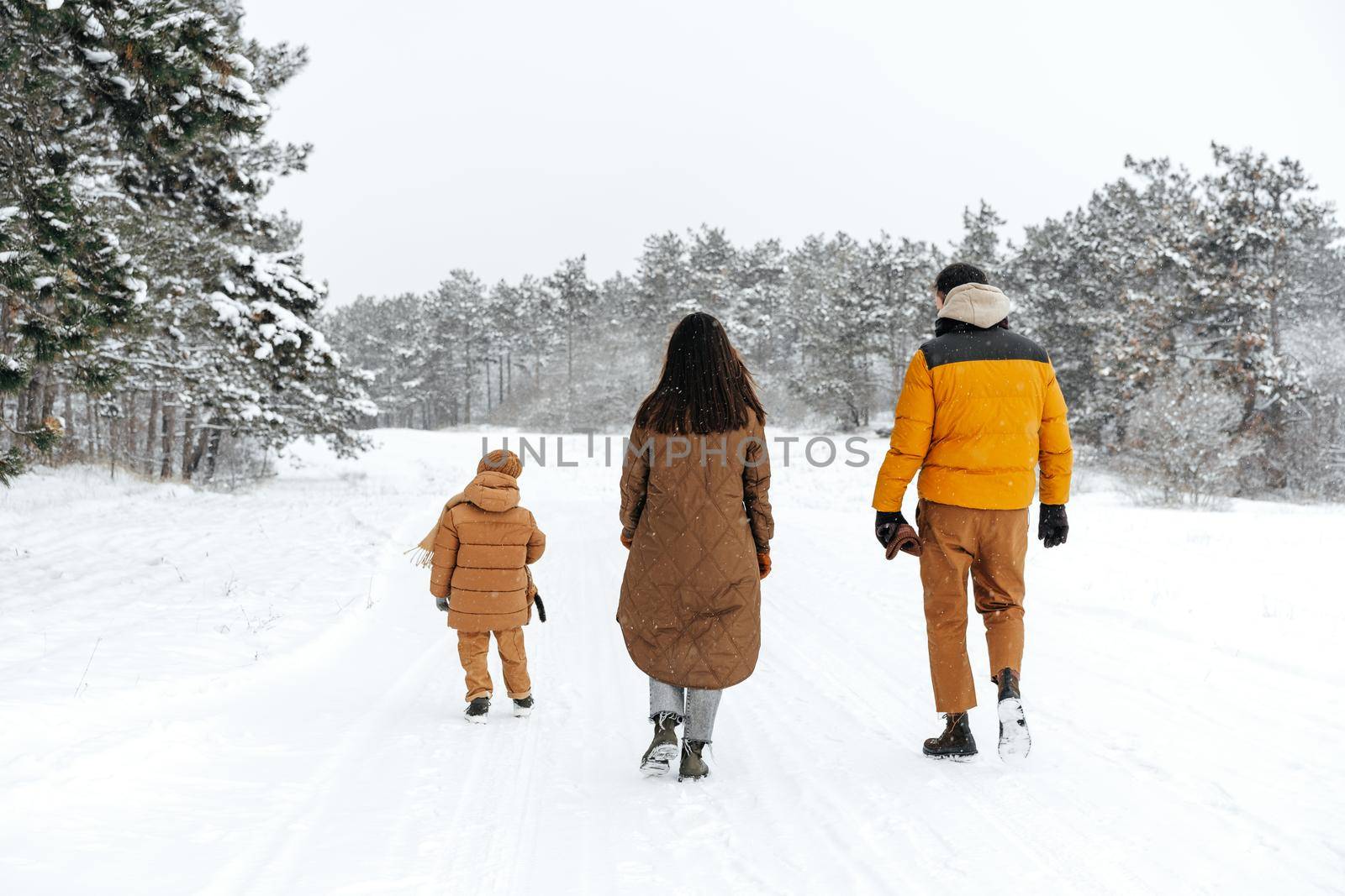 Happy family having a walk in winter outdoors in snow forest