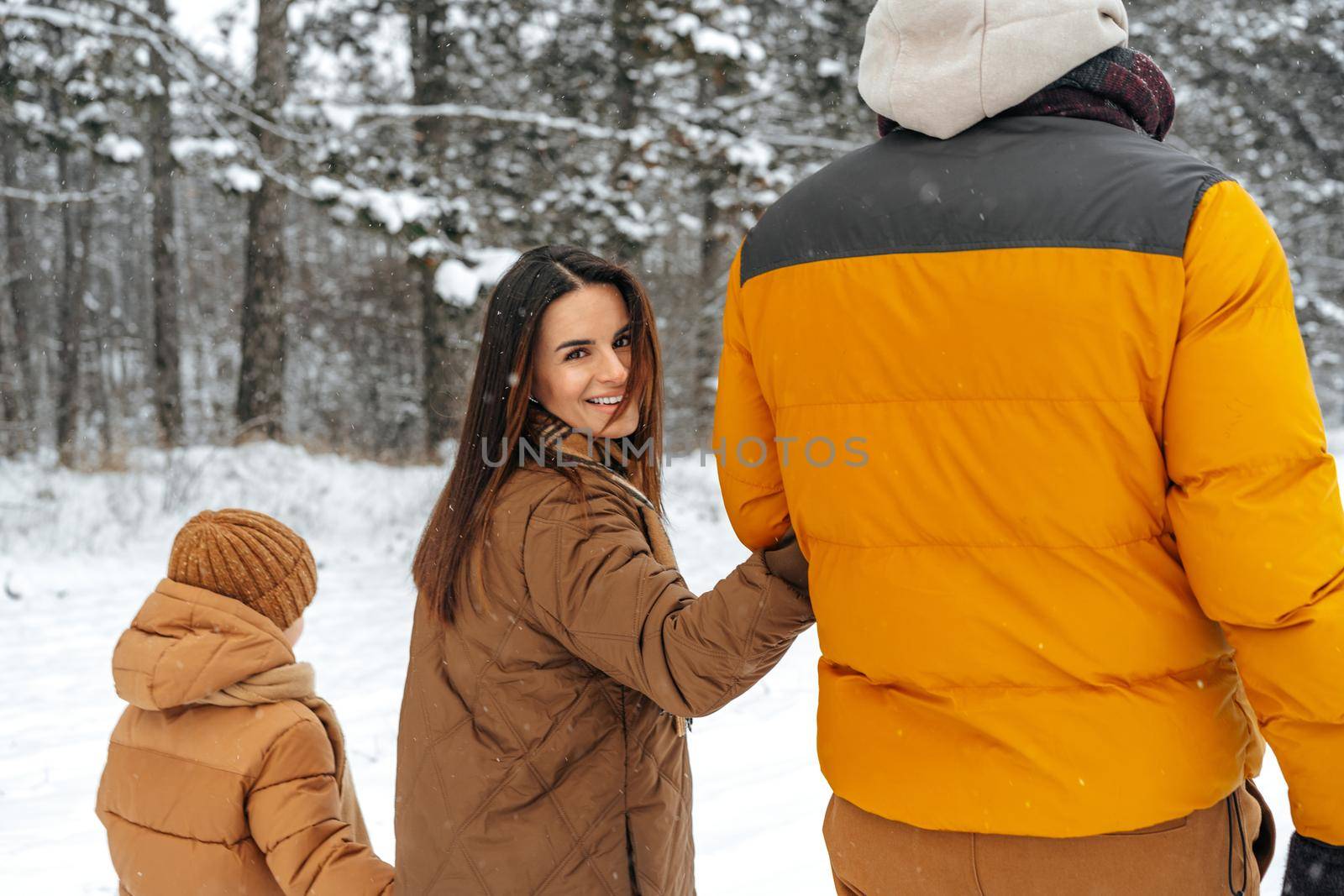 Happy family having a walk in winter outdoors in snow by Fabrikasimf