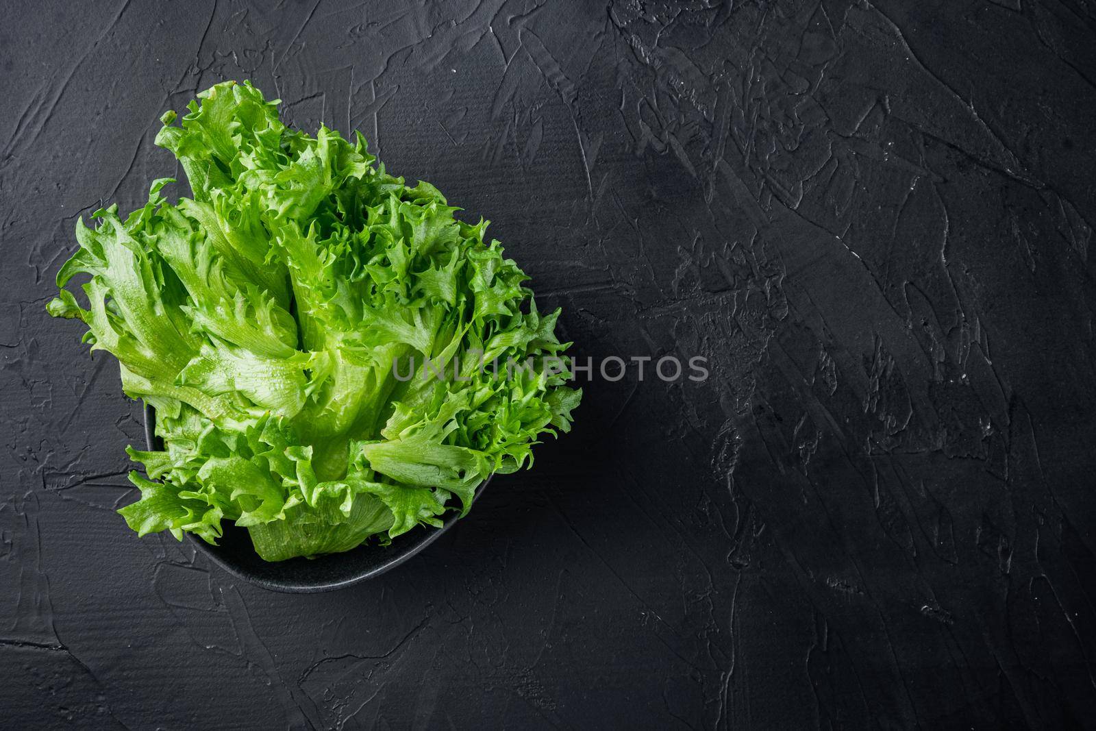 Raw organic green oak lettuce leaves, on black background, top view flat lay with copy space for text