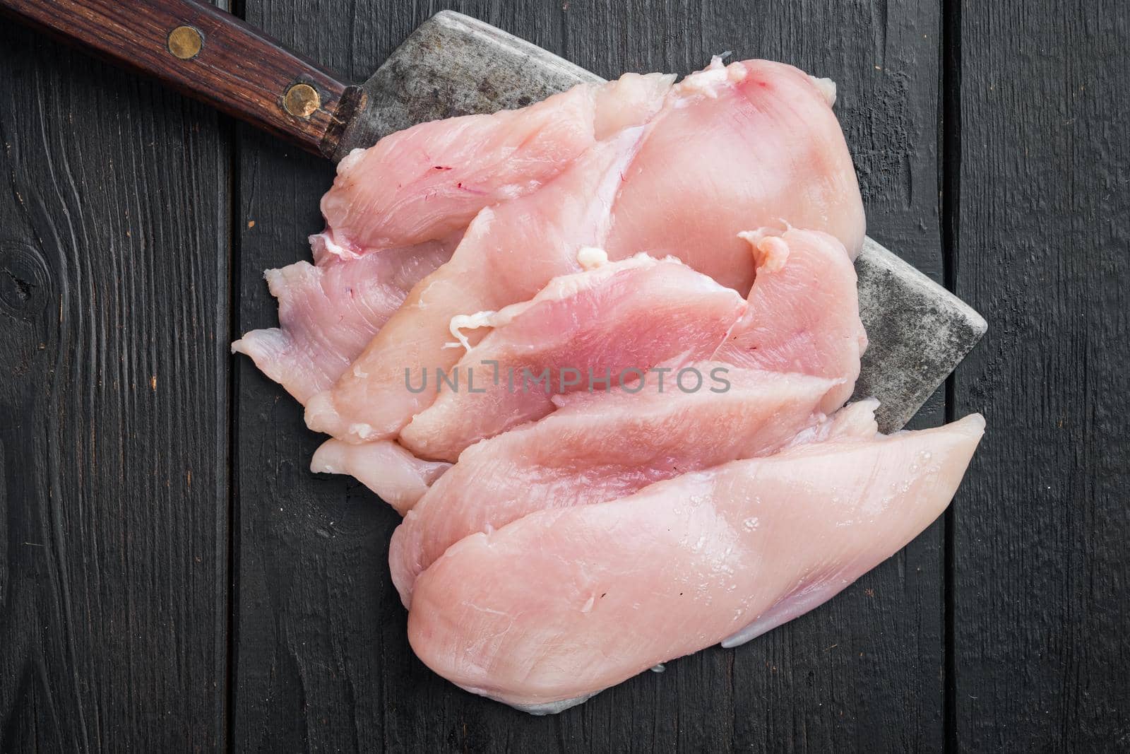 Raw fillet of chicken fillet, on black wooden table background, top view flat lay