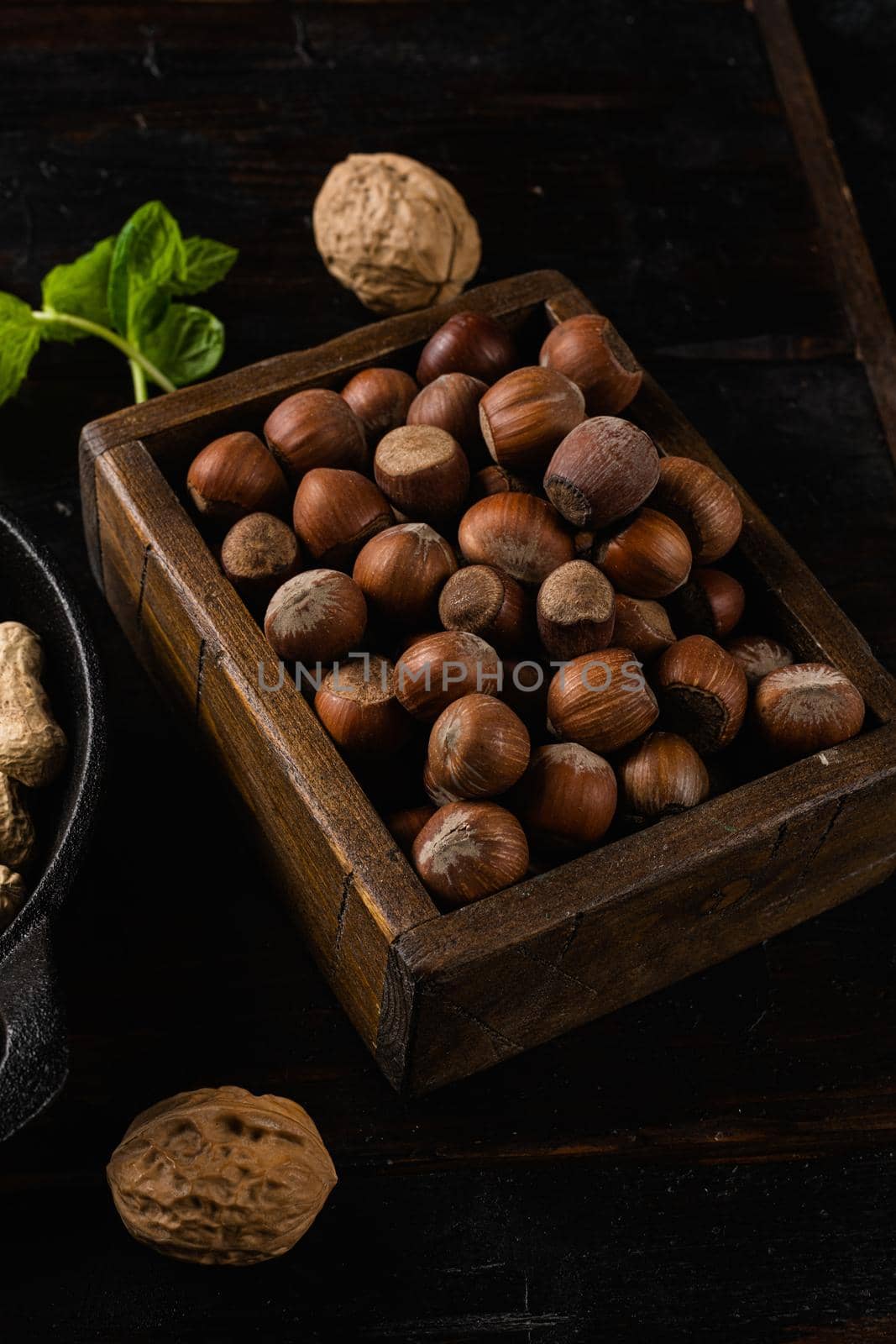 Heap or stack of hazelnuts, on old dark wooden table background by Ilianesolenyi