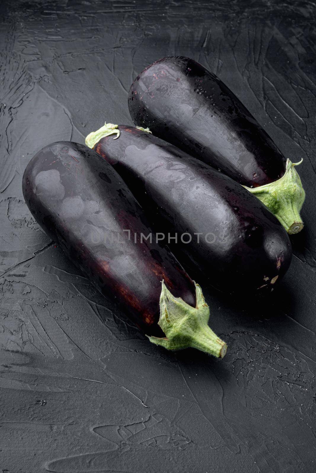 Raw ripe eggplants from the garden farm, on black stone background, with copy space for text by Ilianesolenyi