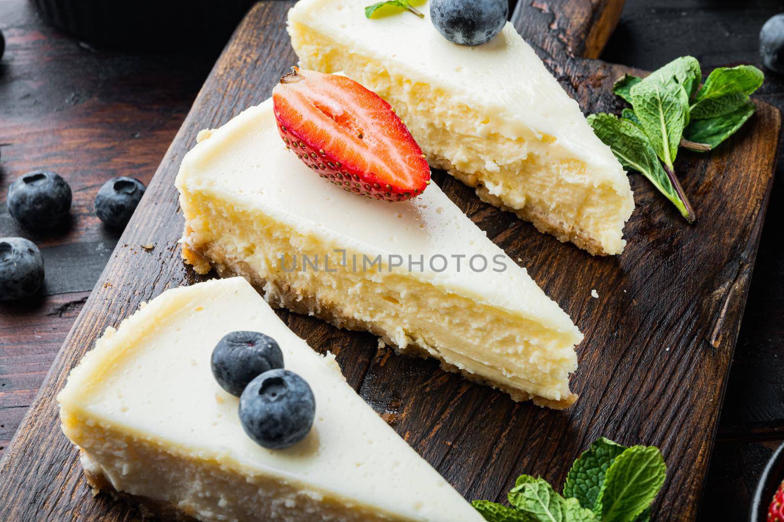 Cheesecake with blueberrie and strawberries, on old dark wooden table background