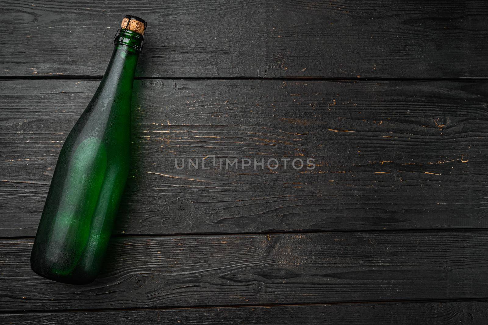 Green Glass bottle of soda water set, on black wooden table background, top view flat lay, with copy space for text