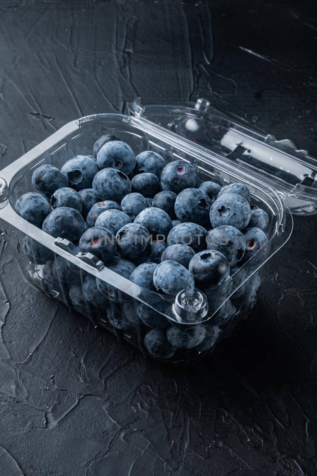 Blueberries, in clear plastic tray, on black background