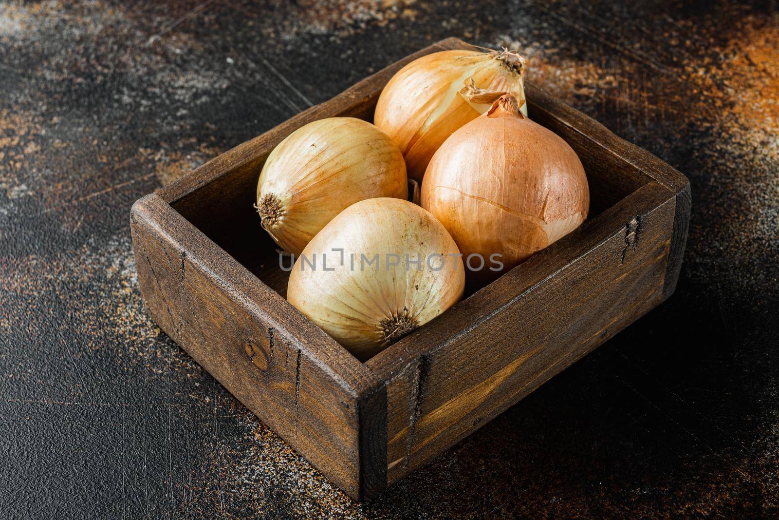 Unpeeled raw yellow onions, on old dark rustic background by Ilianesolenyi