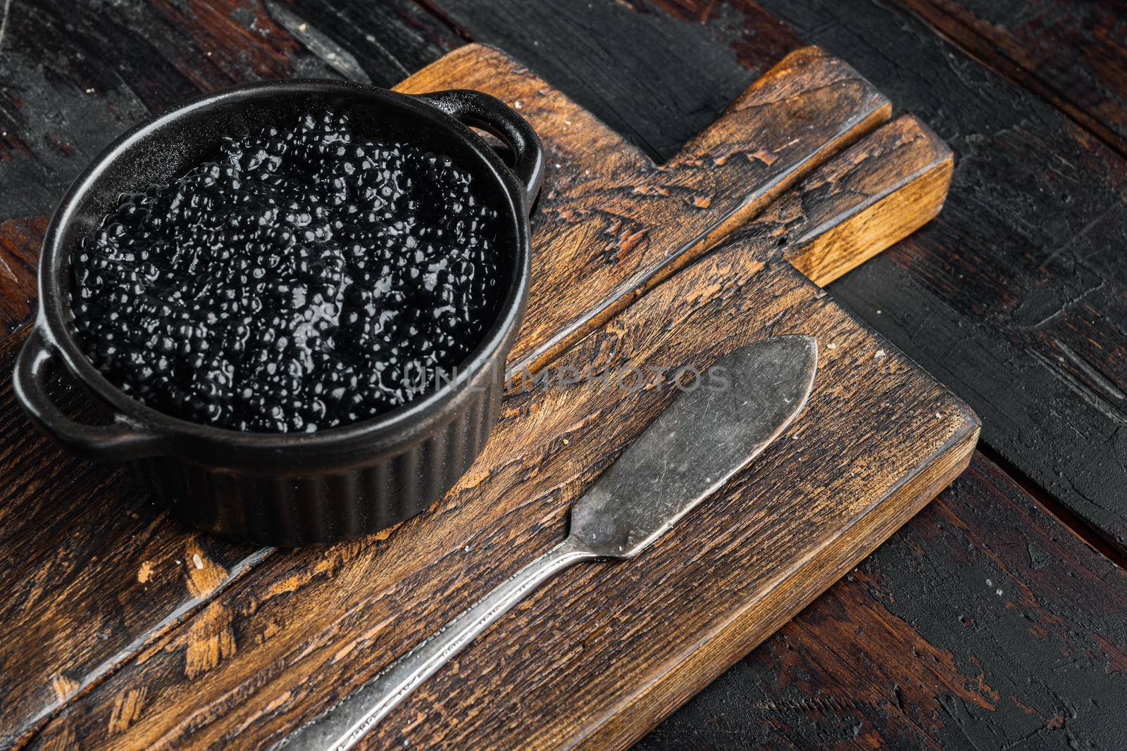 Black sturgeon caviar in bowl, on old dark wooden table background