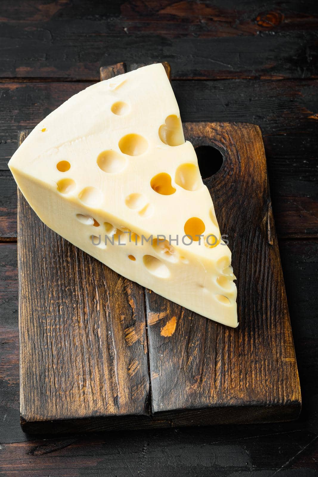 Maasdam cheese, on old dark wooden table by Ilianesolenyi