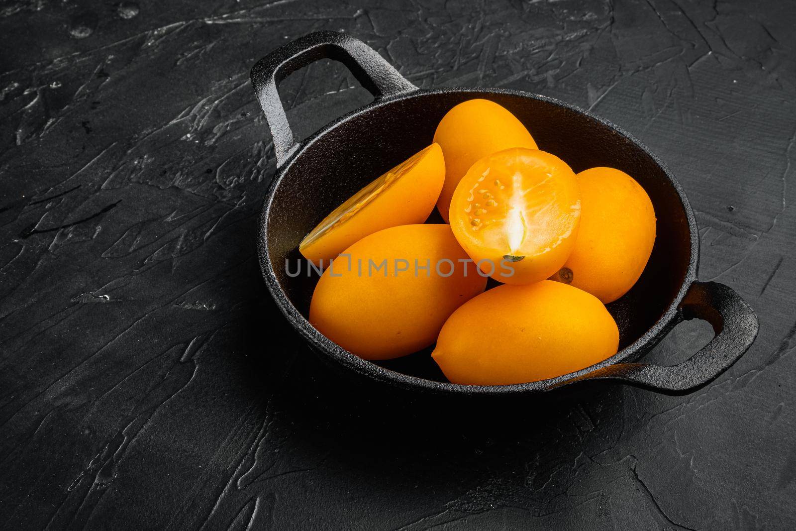 Fresh yellow tomatoes set, on black dark stone table background