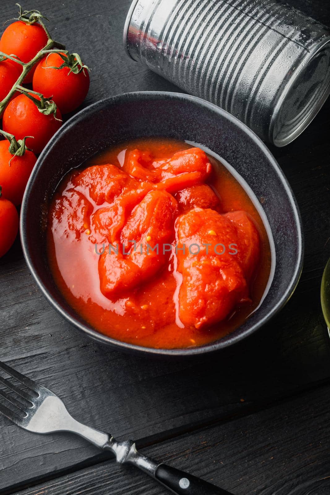 Whole canned tomatoes, on black wooden table background by Ilianesolenyi