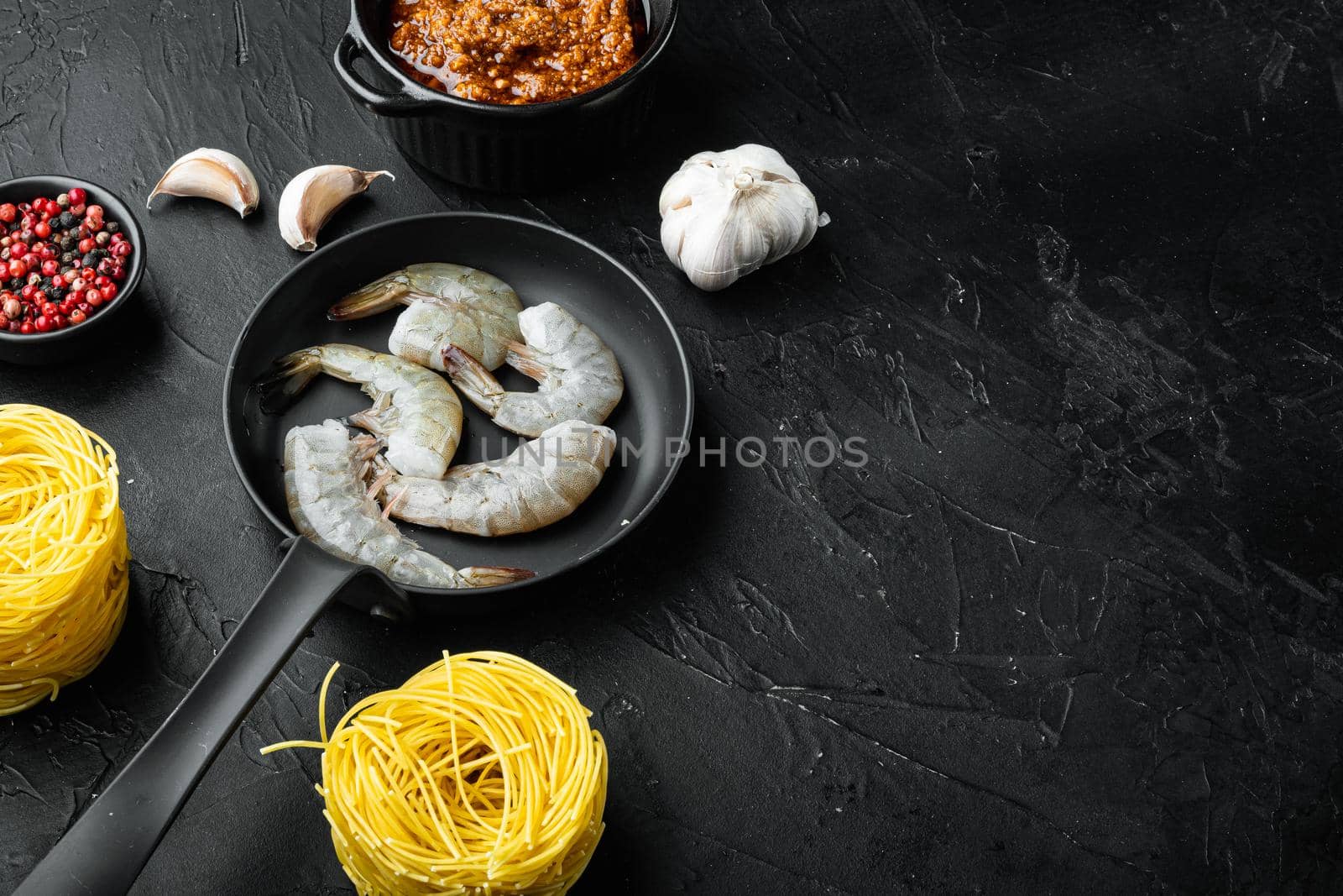 Traditional Italian dish. pasta with pesto ricotta parmesan and grilled seafood ingredients, on black stone background, with copy space for text by Ilianesolenyi