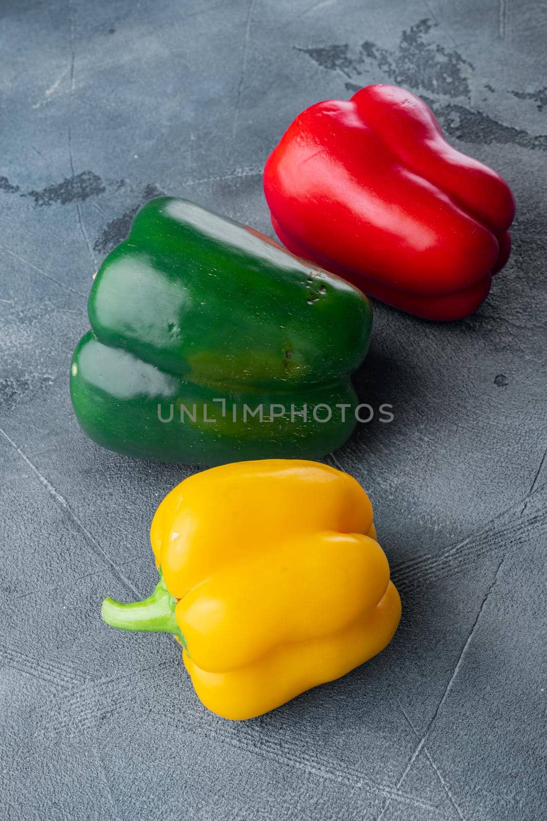Colorful green , red and yellow peppers, on gray background by Ilianesolenyi