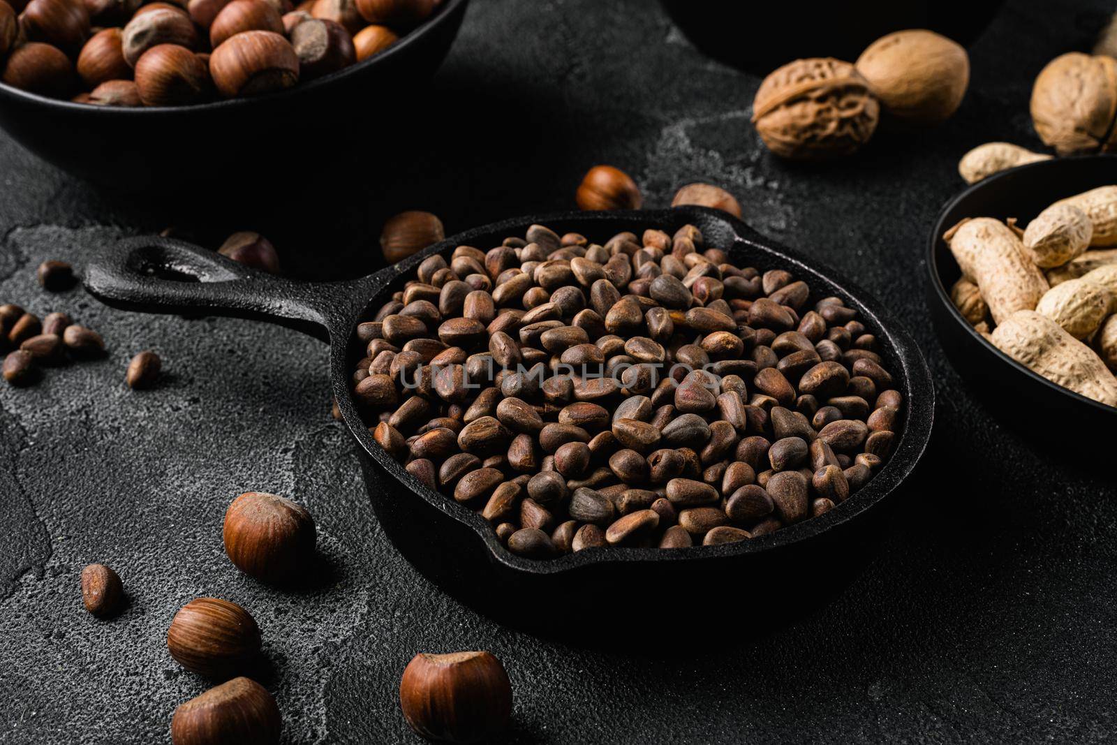 Pine nuts set, on black dark stone table background