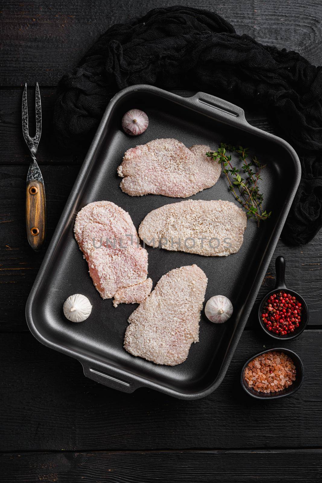 Raw schnitzel chicken meat, on black wooden table background, top view flat lay