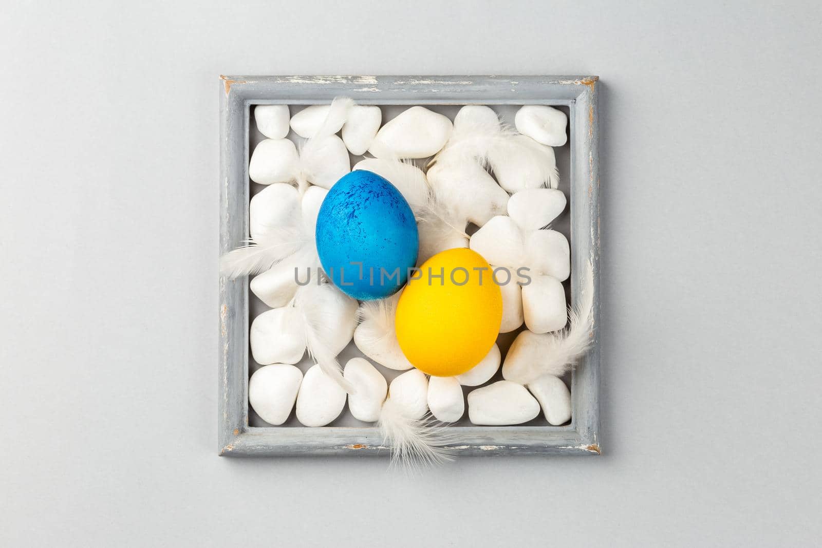 Easter Eggs on the rocks surrounded by the gray frame. Ukrainian Blue and Yellow National flag colors. Support Ukraine 