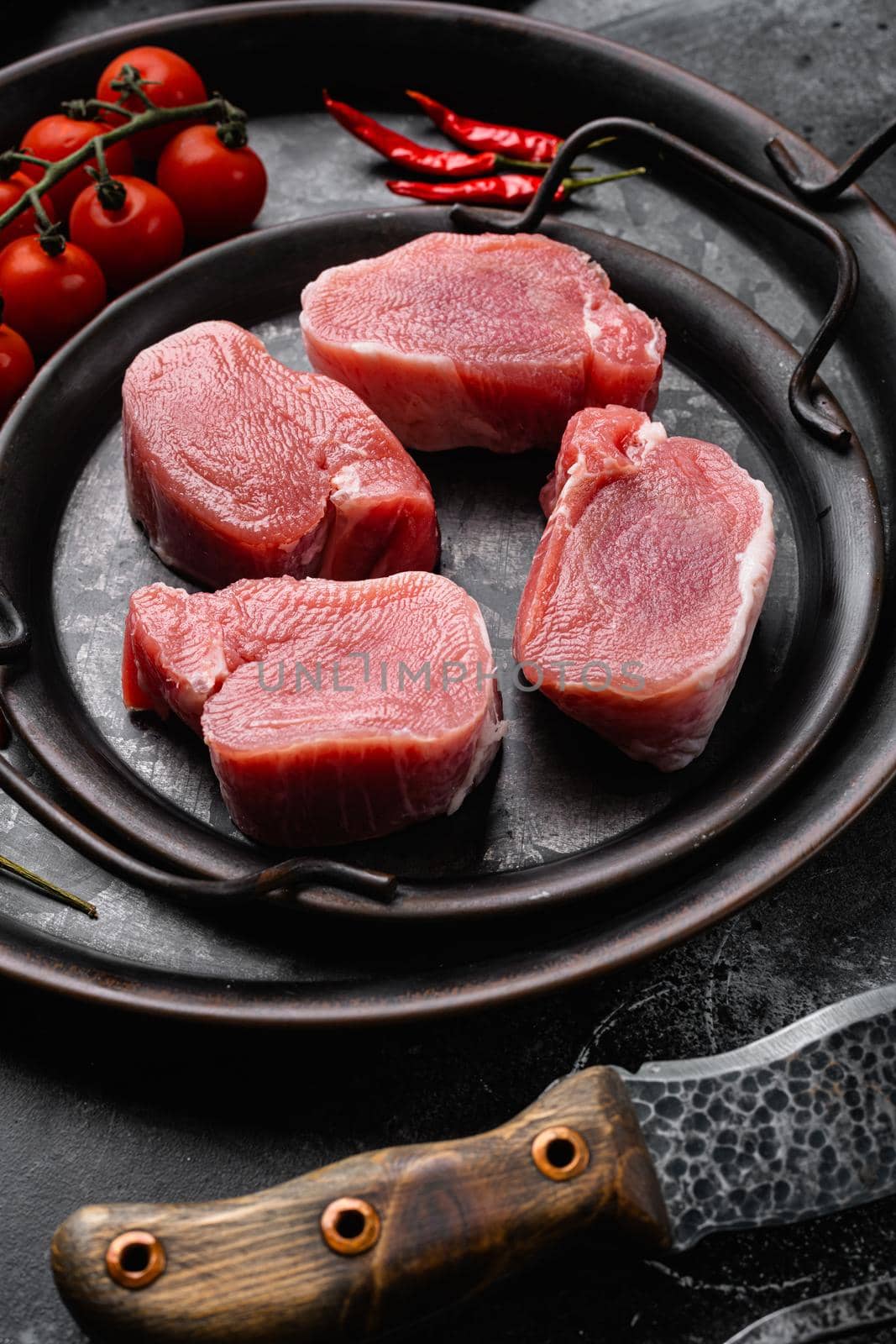 Organic pork meat chops set, on black dark stone table background by Ilianesolenyi