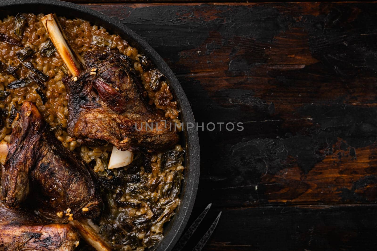 Baked lamb shank with barley and ale set, on old dark wooden table background, top view flat lay, with copy space for text