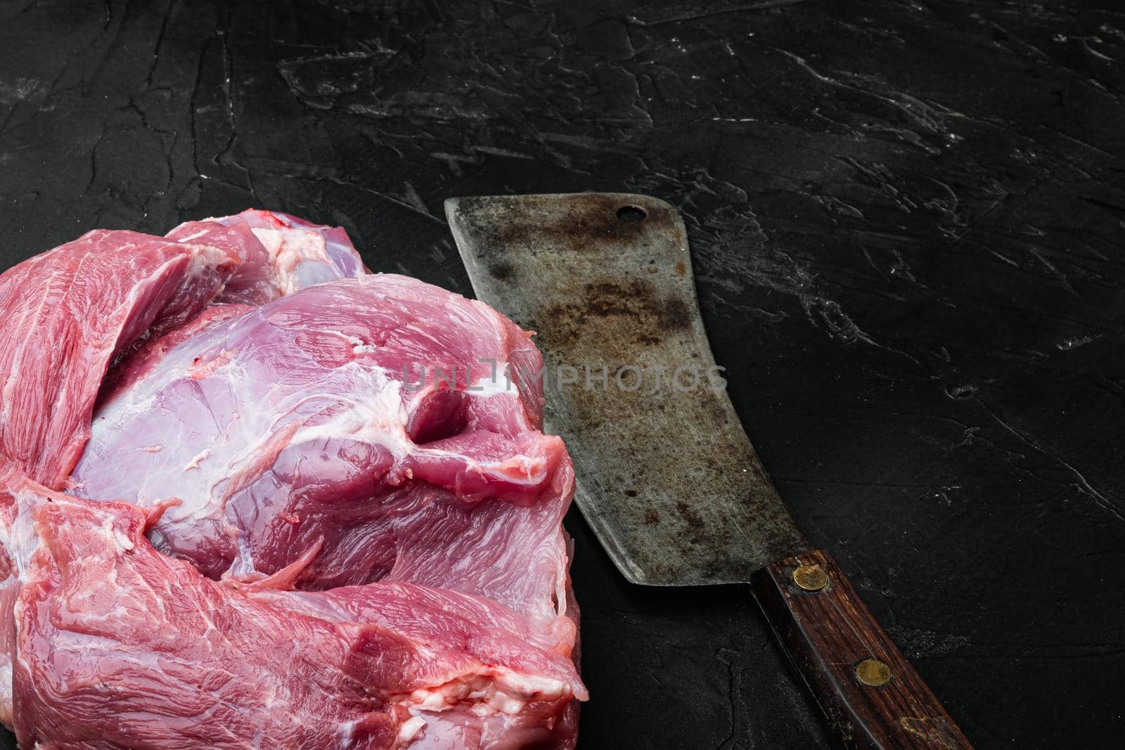 Fresh pork meat , with old butcher cleaver knife, on black dark stone table background, with copy space for text by Ilianesolenyi