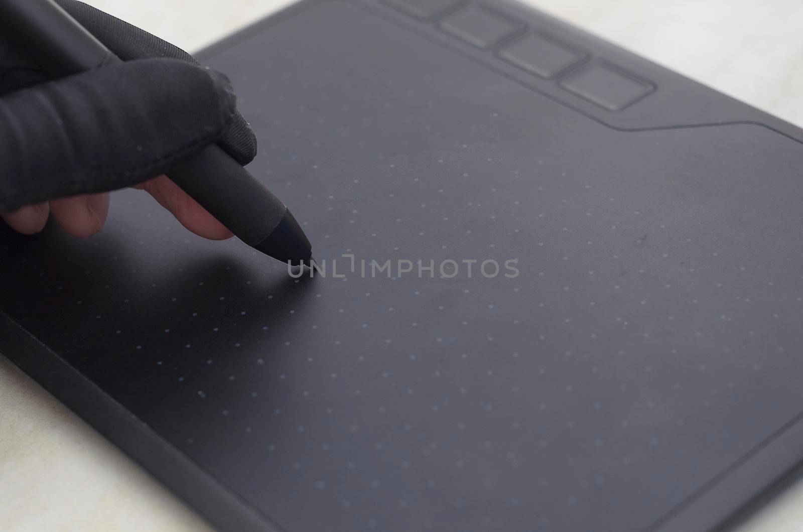 Graphic designer's hand in a black glove draws on the workspace of a graphics tablet,close up.