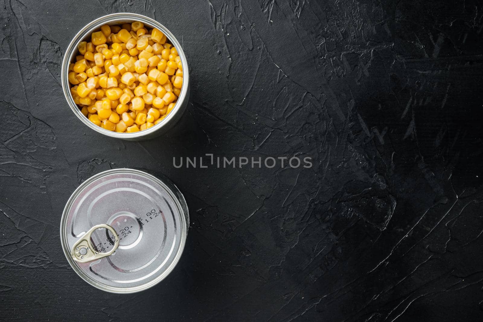 Canned sweet corn in can, on black background, top view flat lay with copy space for text