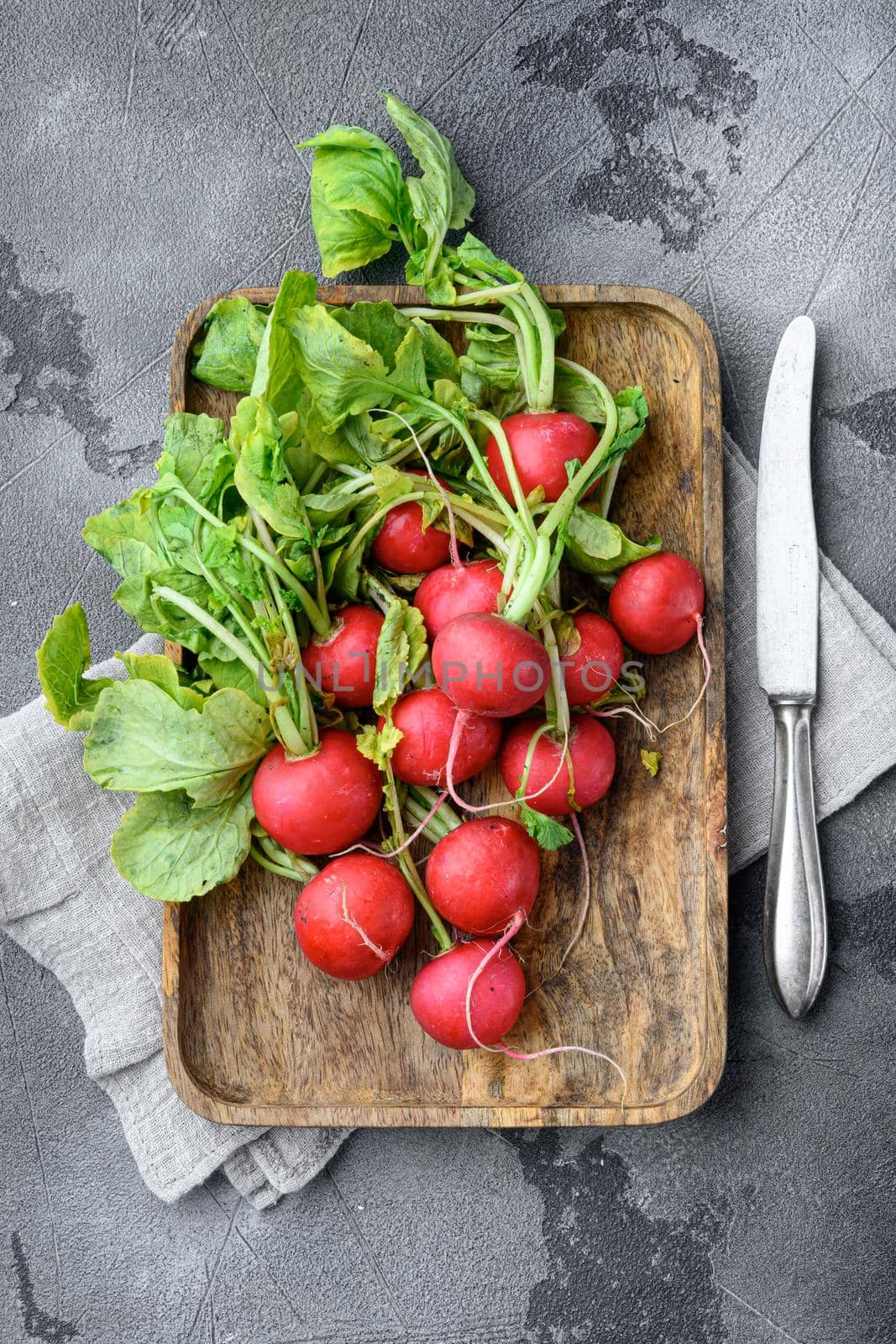 Summer harvested red radish. Growing organic vegetables. Large bunch of raw fresh juicy garden radish set, on gray stone background, top view flat lay