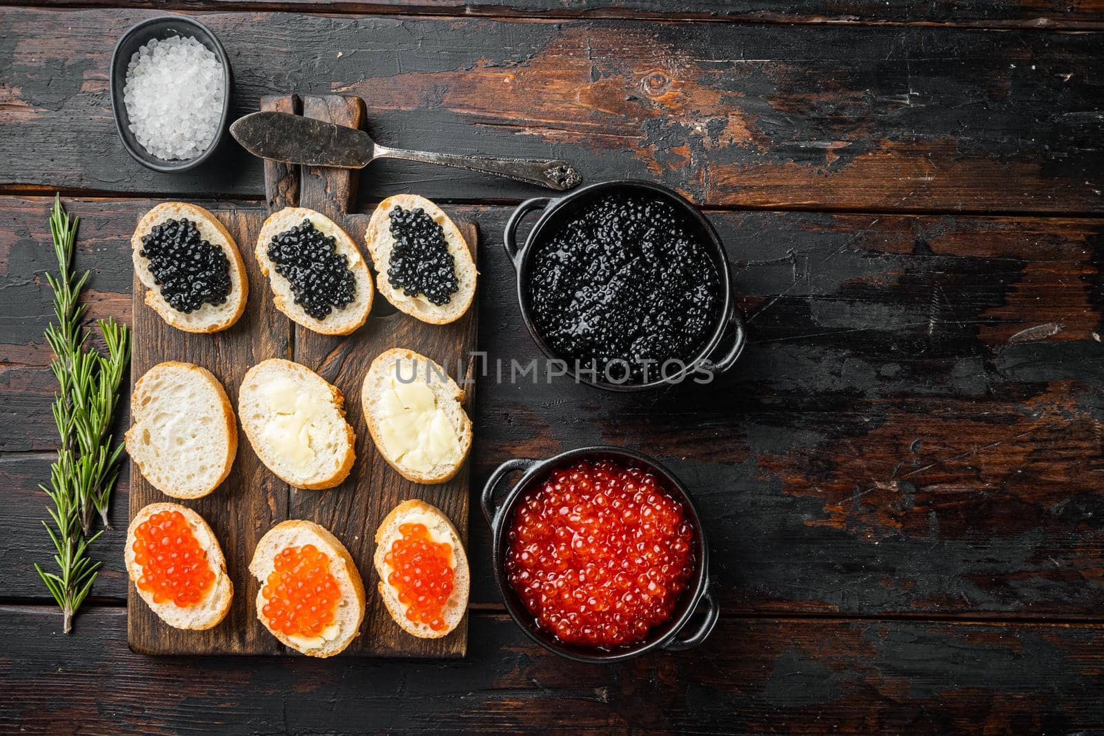 Canapes with black sturgeon, and salmon fish caviar, on old dark wooden table background, top view flat lay